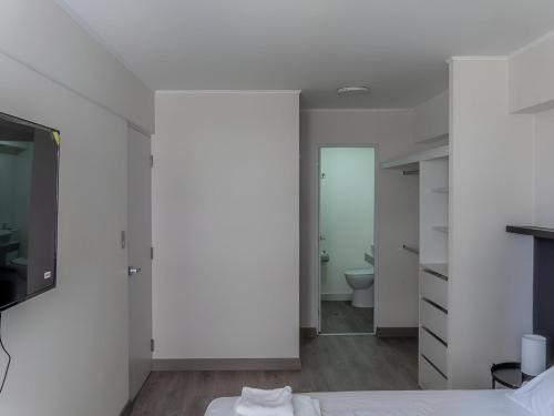 Cette chambre blanche comprend un lit et une salle de bains. dans l'établissement Cozy 2BR Loft in the Heart of Miraflores, à Lima