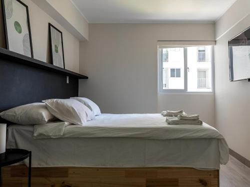 um quarto com uma cama com lençóis brancos e uma janela em Cozy 2BR Loft in the Heart of Miraflores em Lima