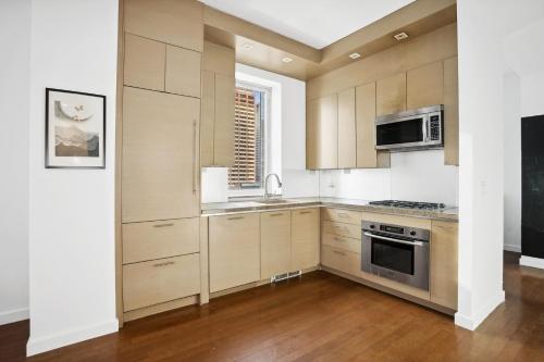 eine Küche mit Holzschränken und Küchengeräten aus Edelstahl in der Unterkunft FURNISHED Oversized 1 Bedroom with Home Office (Short-Term Available) in New York