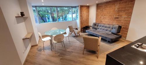 a living room with a couch and a table and chairs at Apartaestudios Margarita in Bogotá