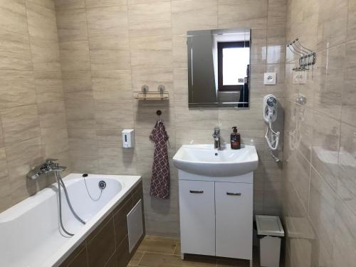 a bathroom with a bath tub and a sink and a bath tub at Penzion U Kostela in Kuželov