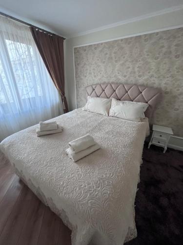 a bedroom with a white bed with two towels on it at Apartament in Botosani in Botoşani