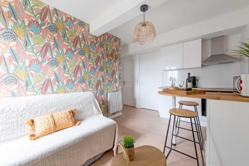 un salon avec un canapé blanc et une cuisine dans l'établissement Le Tropical : T2 rénové Ambiance Cosy et Colorée, à Mazamet