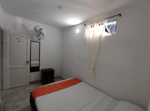 a white bedroom with a bed and a window at Cabaña Gaia Rodadero in Santa Marta