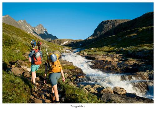 Deux personnes avec des sacs à dos marchant le long d'une rivière dans l'établissement Turtagrø Hotel, à Fortun