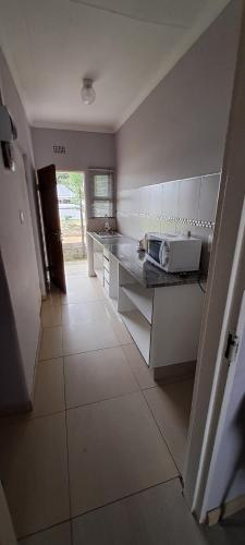 a kitchen with white cabinets and a white tile floor at Matat Studio Apartments in Matatiele