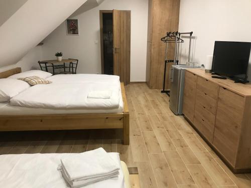 a bedroom with two beds and a flat screen tv at Penzion U Kostela in Kuželov