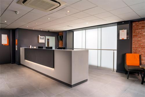 an office lobby with a reception desk and orange chair at easyHotel Glasgow City in Glasgow