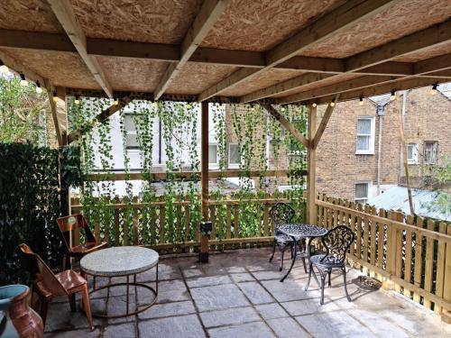 een patio met tafels en stoelen op een houten terras bij SureBillionaire Homes II in Londen