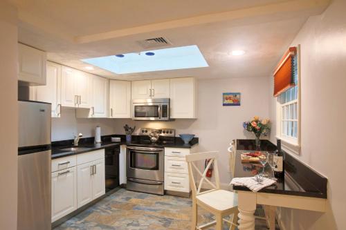 a kitchen with white cabinets and a table in it at Pleasant Bay Village Resort in Chatham