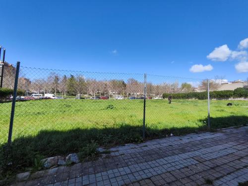 a fence in front of a field of grass at San Centro IFEMA Wizink Metropolitano Airport Apartments in Madrid