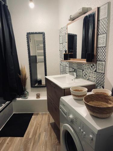 une salle de bain avec une machine à laver et un lavabo dans l'établissement Maison « l’effet-mère »en rez de chaussée , à Aigues-Mortes