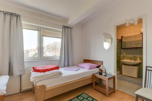 a bedroom with a bed with pink pillows and a window at Vila Ida in Zagreb