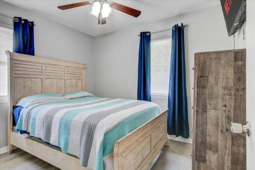 a bedroom with a bed with blue curtains and a fan at Comfy 3 bedroom home w/ fenced yard in Bridge City