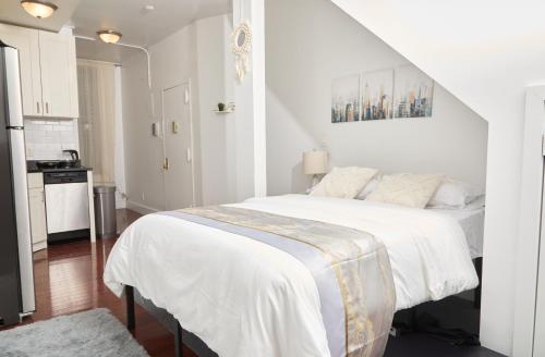 a white bedroom with a large bed and a kitchen at Private Loft in Hells Kitchen near Times Square in New York