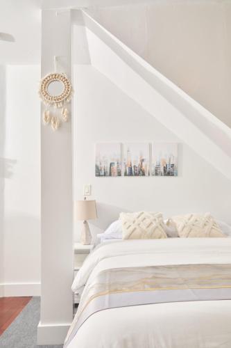 a bedroom with white walls and a white bed at Private Loft in Hells Kitchen near Times Square in New York