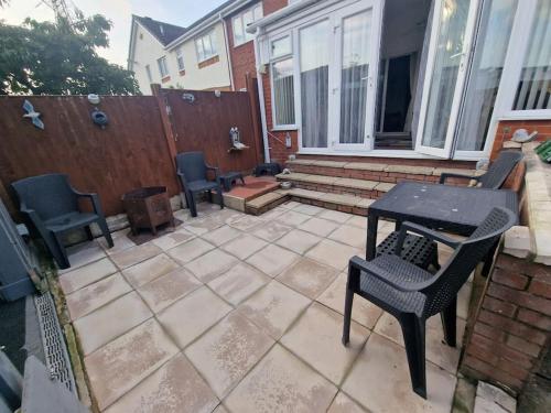 a patio with chairs and a table and a fence at Spacious 3bed semi/Gamesroom/Drive/10mins to City in Wrexham