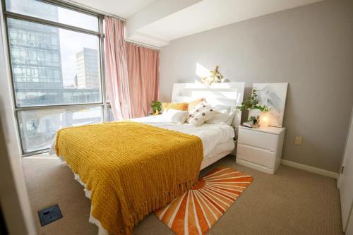 a bedroom with a bed with a yellow blanket and a window at Cozy Suite in Heart of Downtown Toronto G3 in Toronto