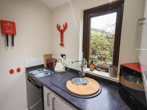 un bancone della cucina con lavandino e finestra di Corner Cottage a Troutbeck