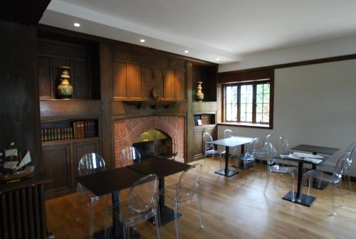 a dining room with tables and chairs and a fireplace at Manoir Dalmore in Névez