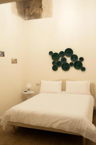 a white bed with green plates on the wall at Le Casine di Spaccanapoli in Naples