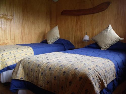 two beds in a room with blue and white sheets at Cabañas Tokerau in Hanga Roa