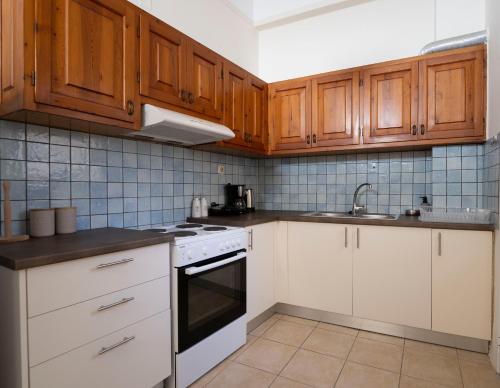 a kitchen with wooden cabinets and white appliances at Cozy Apartment in Hermoupolis in Ermoupoli