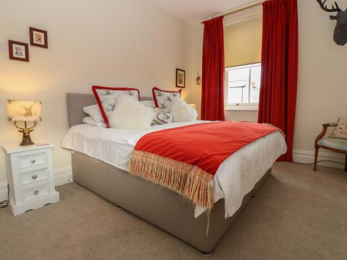 a bedroom with a bed with red curtains and a window at The Back House in Staindrop