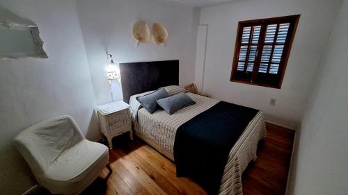 1 dormitorio con 1 cama, 1 silla y 1 ventana en La Querencia Apart RC en Río Cuarto