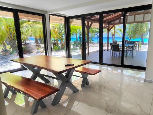 una mesa y bancos en una habitación con vistas al océano en Blue Lagoon Villa en Avatoru