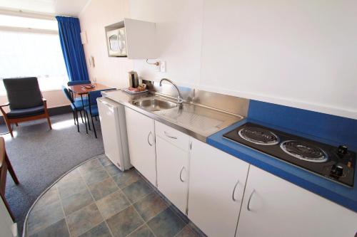 a small kitchen with a sink and a stove at Golden Glow Motel in Rotorua