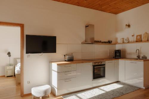 a kitchen with white cabinets and a flat screen tv at Staudingerhof in Staudach-Egerndach