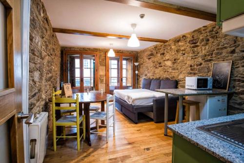 cocina y sala de estar con mesa y cama en Alda Fogar Natural, en Santiago de Compostela