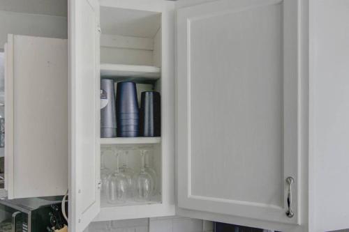 a white cabinet with wine glasses in it at Spacious 3 bedroom home with fenced yard in Groves