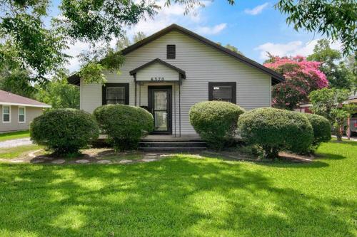 a white house with bushes in front of a yard at Spacious 3 bedroom home with fenced yard in Groves