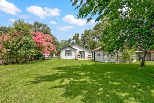 a large yard with a white house and trees at Spacious 3 bedroom home with fenced yard in Groves