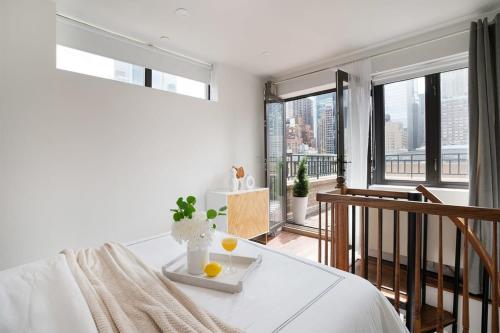 a white bedroom with a table with two oranges on it at 809-6A NEW 2BR Private Roof & City View in New York