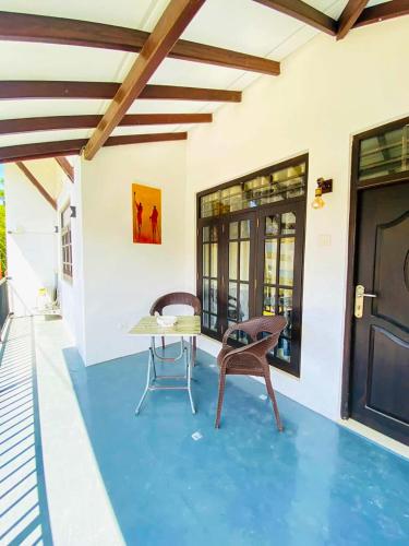 a patio with a table and chairs on a blue floor at OVIYA Guest & Rest in Weligama