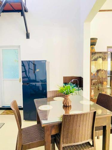 a dining room with a table and chairs and a refrigerator at OVIYA Guest & Rest in Weligama