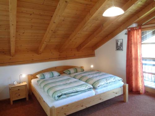 a bed in a room with a wooden ceiling at Haus Fellner**** in Brannenburg