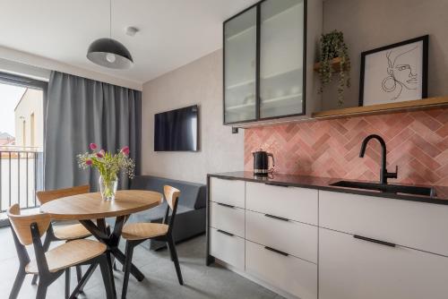 a kitchen and dining room with a table and a sink at AVAPARTS Apartament ROSE in Jastarnia