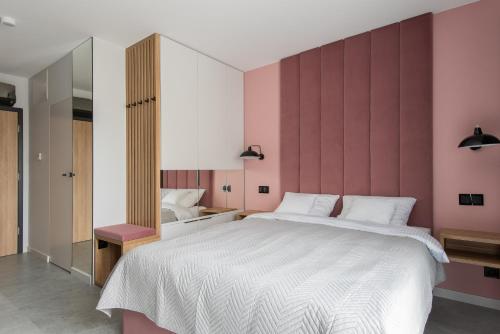 a bedroom with a large white bed with pink walls at AVAPARTS Apartament ROSE in Jastarnia