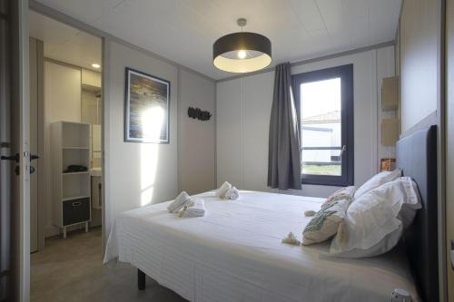 una camera da letto con un grande letto bianco con una finestra di Le Chalet Aquila - Welkeys a Saubrigues