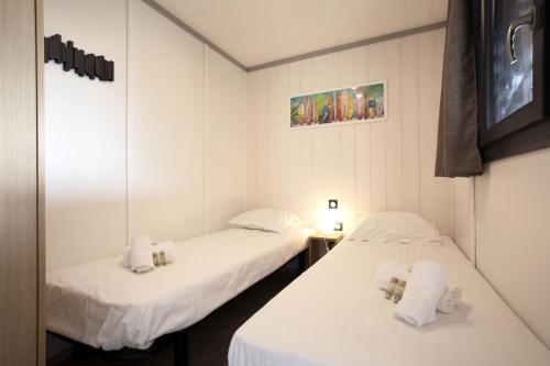 - 2 lits dans une chambre avec des draps blancs et des serviettes dans l'établissement Le Chalet Aquila - Welkeys, à Saubrigues