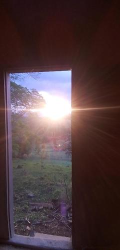una ventana abierta con el sol brillando a través de ella en Chalé Ângico, en Aiuruoca