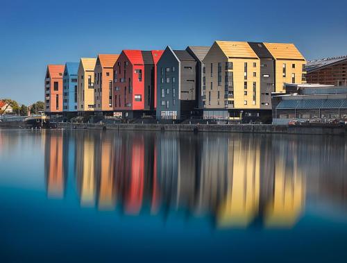 une rangée de bâtiments colorés à côté d'une masse d'eau dans l'établissement Charme des quais, proche centre et plage, à Dunkerque