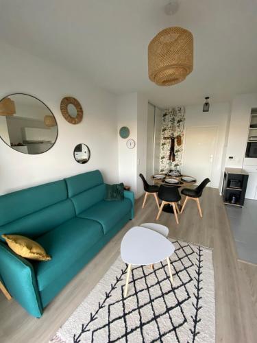 a living room with a green couch and a table at Charme des quais, proche centre et plage in Dunkerque