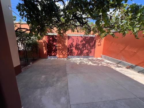 a building with a red fence and a sidewalk at Casa Amigable y Confortable in Yacuiba
