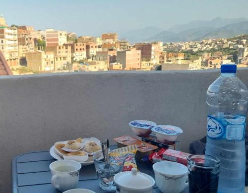 einen Tisch mit Teller mit Lebensmitteln und einer Flasche Wasser in der Unterkunft bejaia room in Bejaïa