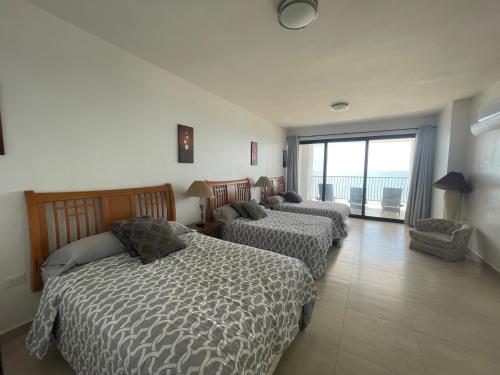 a bedroom with three beds and a large window at Hermosa casa a la orilla del mar in Bahía Kino